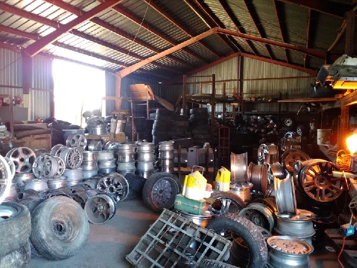 Used auto parts and wheels in a warehouse setting.