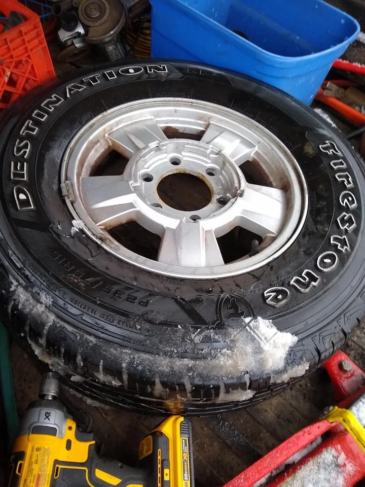 Used tire and rim resting on a workbench.