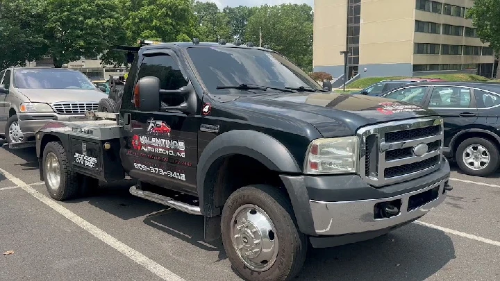 Valentino's Auto Recycling tow truck in a parking lot.