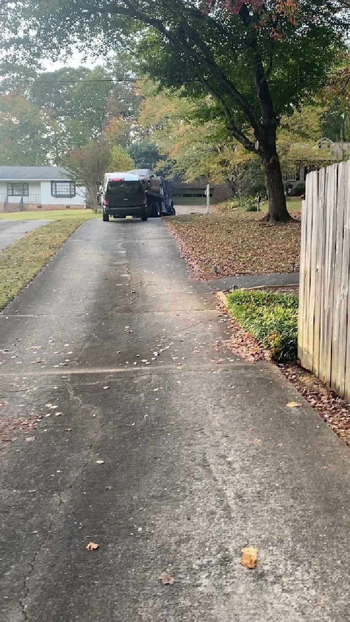 Vehicle being loaded on a truck in a driveway.