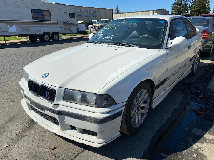 White BMW parked on the street, slightly dirty.