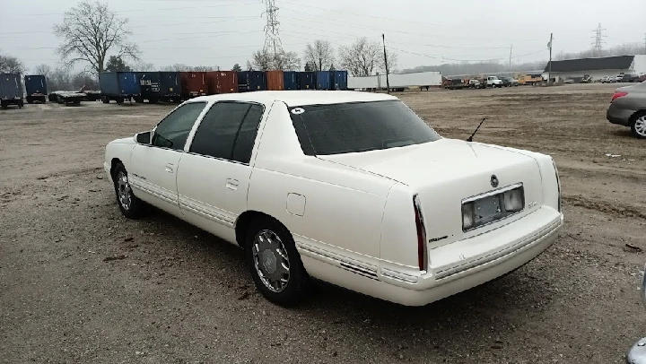 White car parked in a junkyard setting.