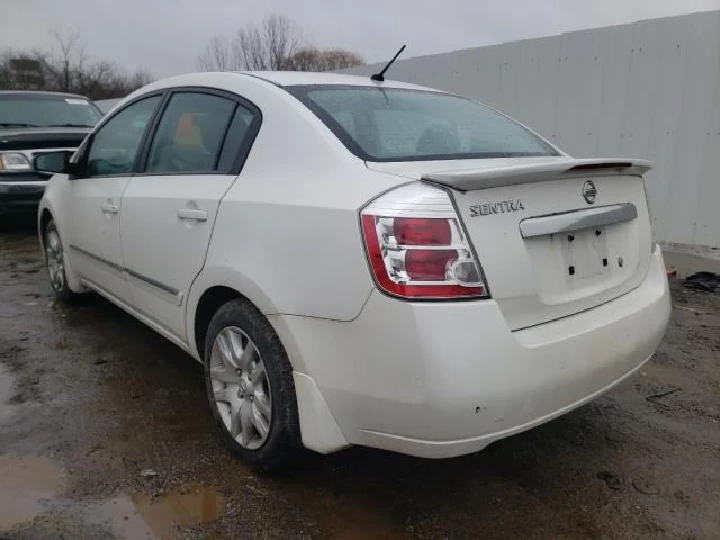 White Nissan Sentra parked in a junkyard.