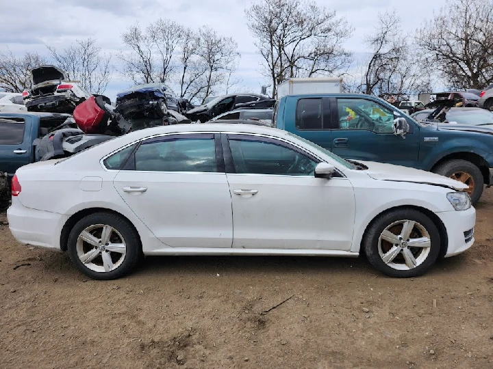 White sedan parked in a junkyard among cars.