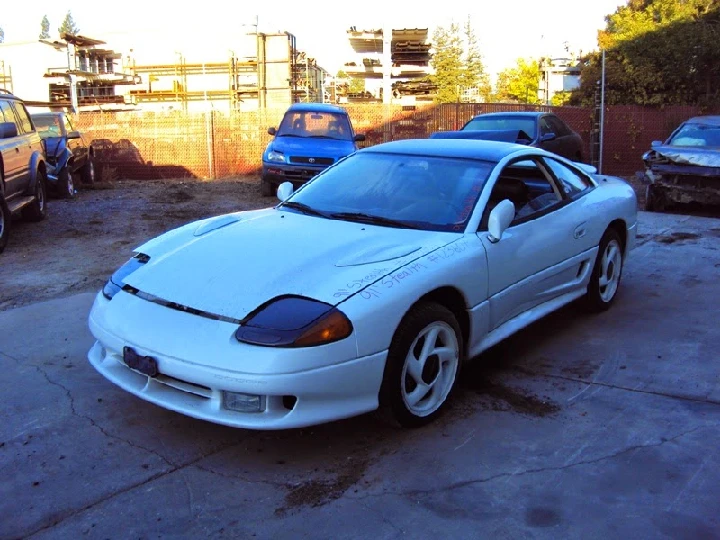 White sports car in a recycling yard.