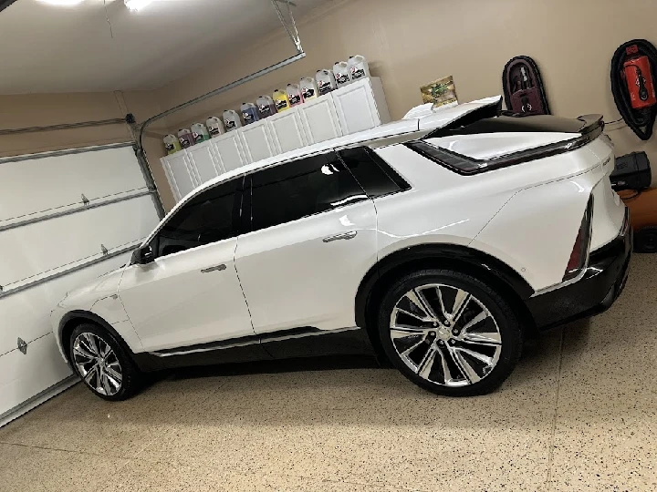 White SUV parked in a garage with tools visible.