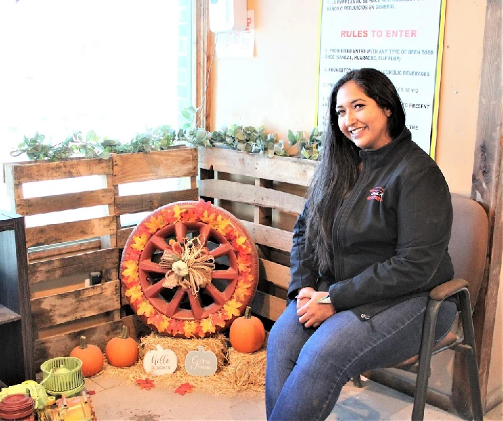 Woman sitting by a decorated autumn display.