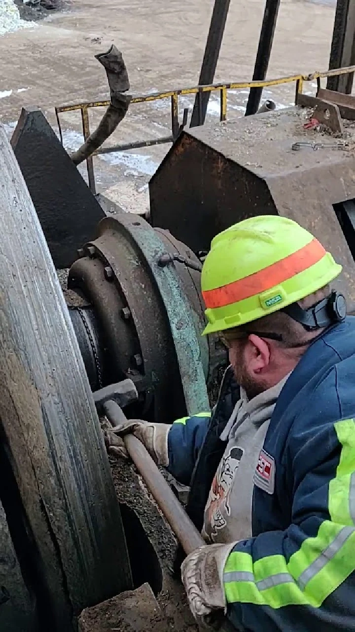 Worker repairing machinery at SA Recycling facility.