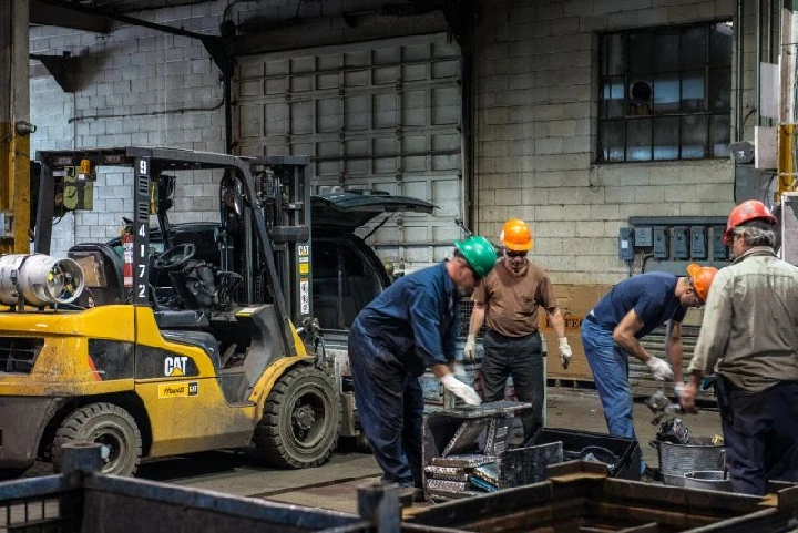 Workers handling equipment in an auto shop.