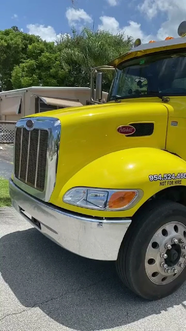 Yellow tow truck in a sunny outdoor setting.