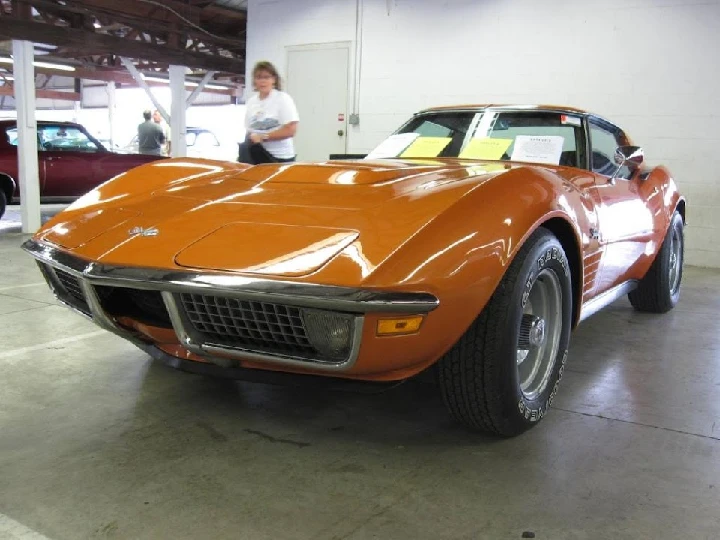 1970s orange sports car in a showroom setting.