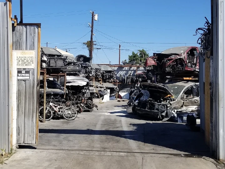 Auto dismantling yard with various vehicles and parts.