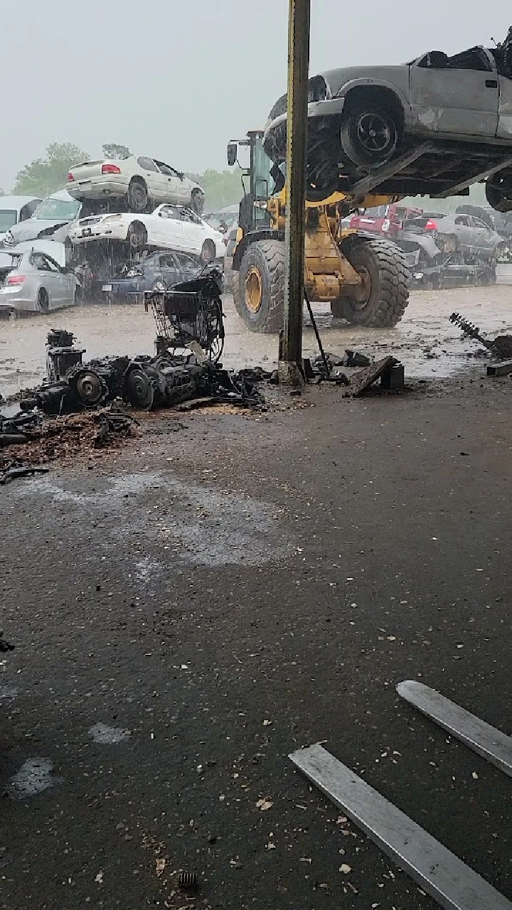 Auto parts yard with stacked vehicles and machinery.