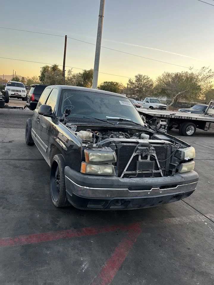 Car with open hood at El Valle Auto Parts yard.