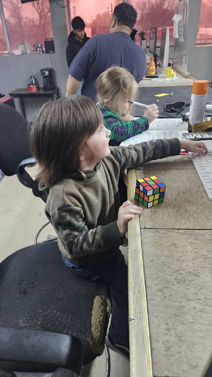 Children playing with a Rubik's Cube at a desk.