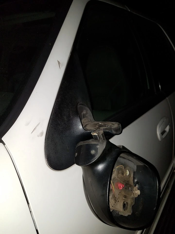 Damaged car mirror on a white vehicle.