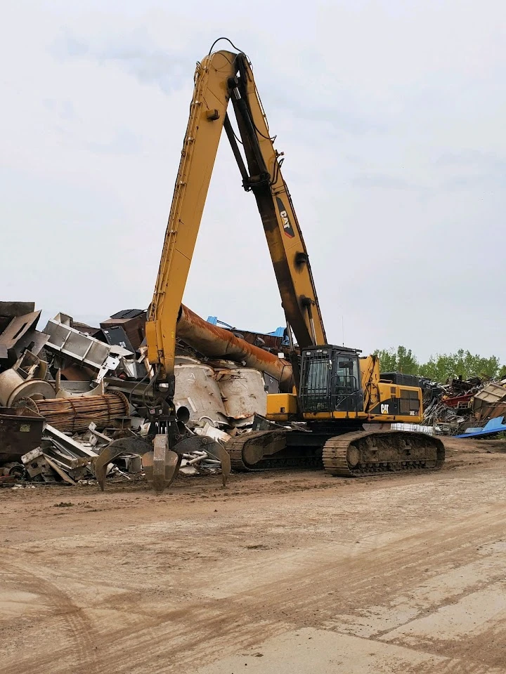 Excavator handling scrap metal at a waste facility.