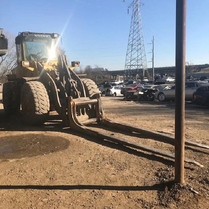 Heavy loader on a dirt lot with parked vehicles.