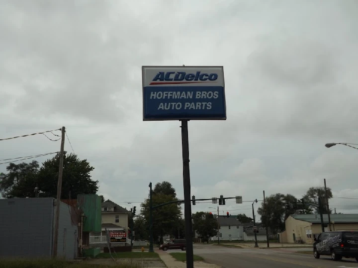 Hoffman Bros Auto Parts sign with cloudy sky backdrop.