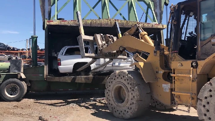 Loader lifting a vehicle at an auto wrecking yard.