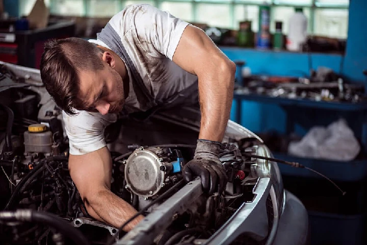 Mechanic working on a car engine in a workshop.