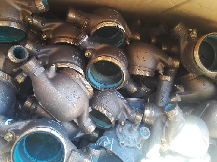 Metal plumbing parts stacked in a recycling box.