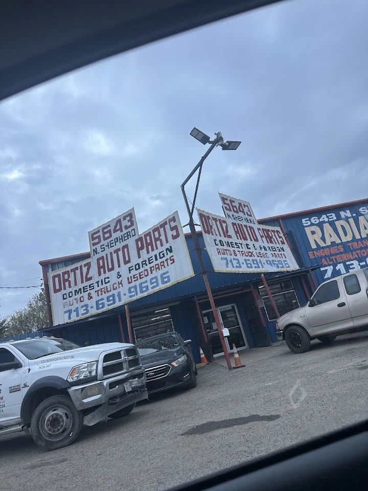 Ortiz Auto Parts storefront with parked vehicles.