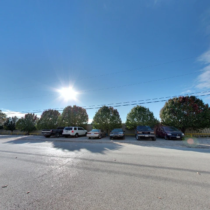 Parking lot with vehicles and trees under blue sky.