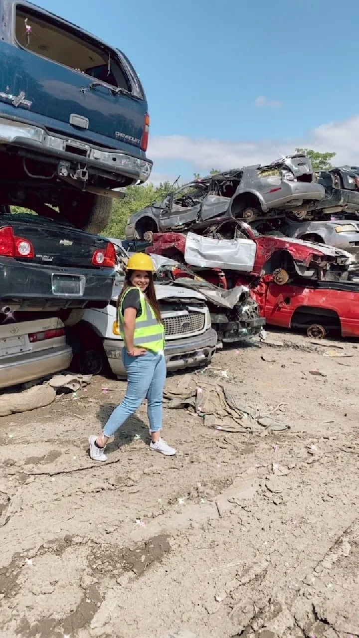 Person in safety gear at auto salvage yard.