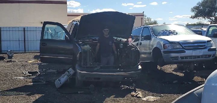 Person working on an SUV in a junkyard.