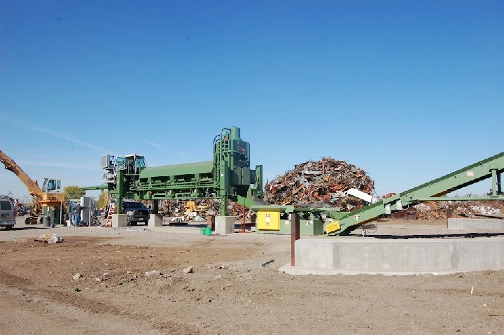 Recycling facility with heavy machinery and scrap pile.