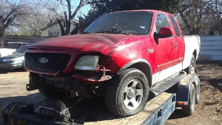 Red junk pickup truck on a trailer.