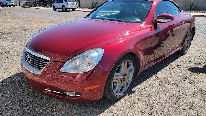 Red luxury coupe parked in salvage yard.