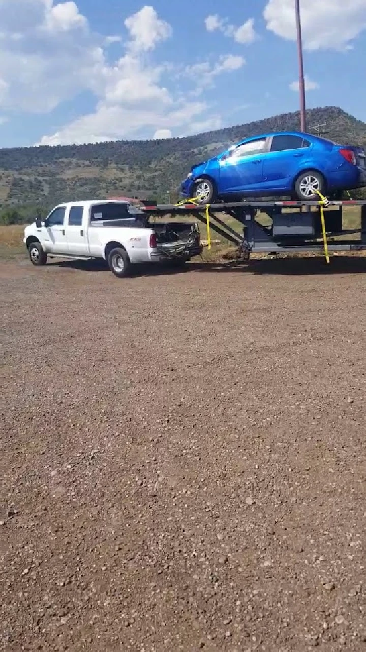 Tow truck loading a blue car at A & G Auto Wrecking.