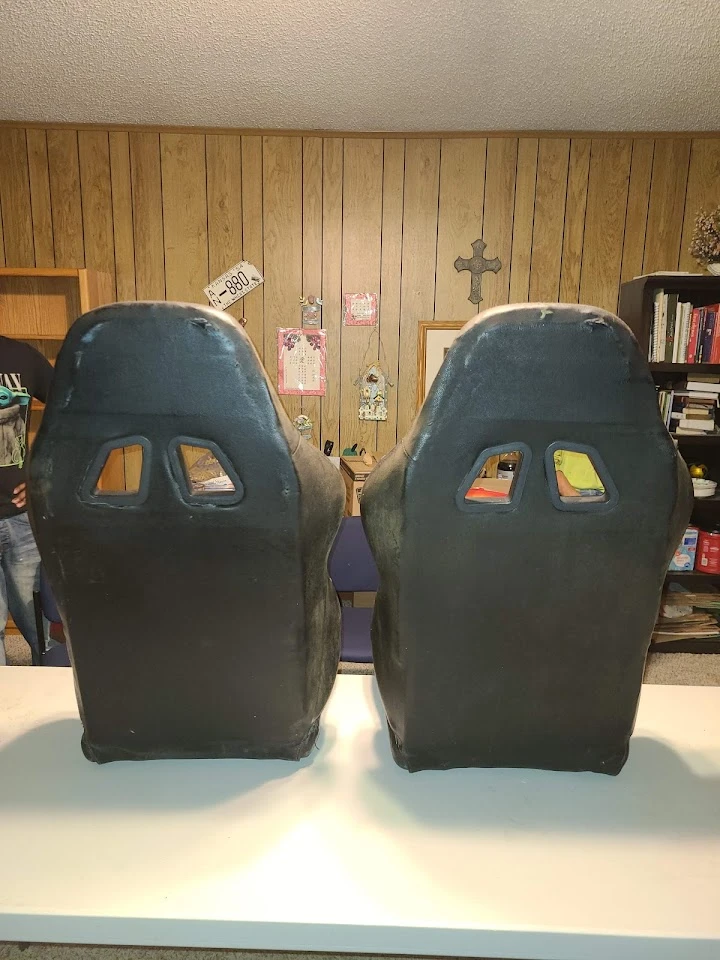 Two car seats on a table in a wood-paneled room.