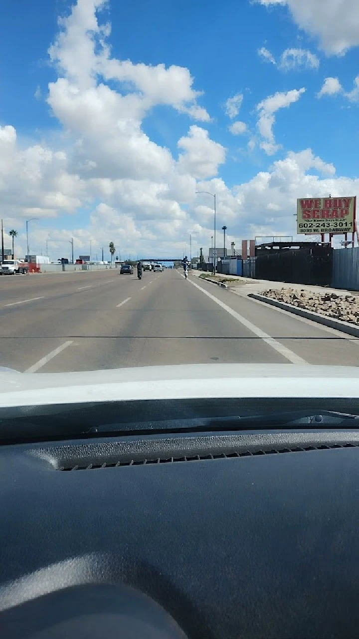 View of a road with clouds and a sign ahead.