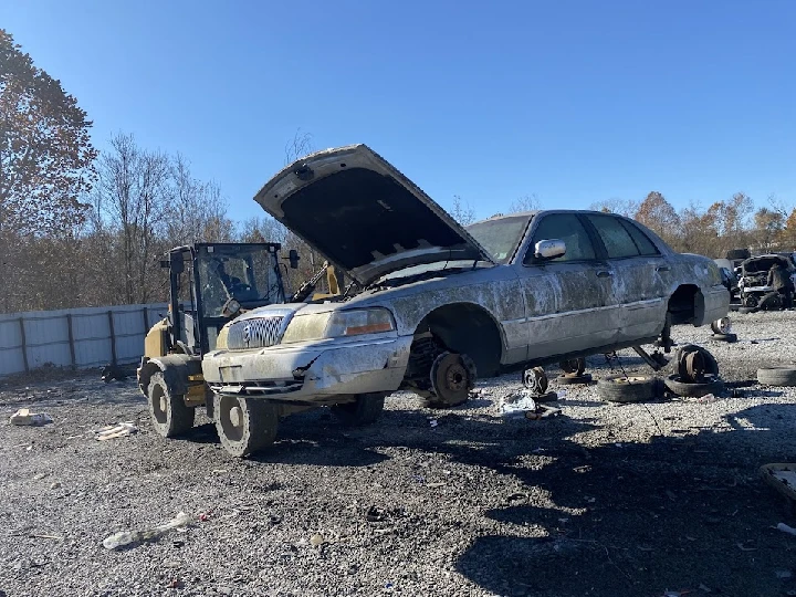 Abandoned car with raised hood in salvage yard.