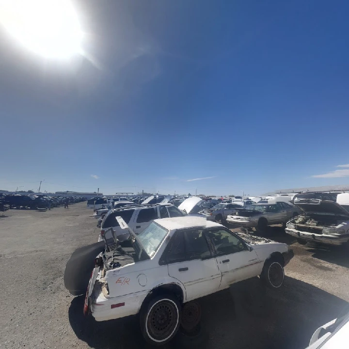 Abandoned cars in a junkyard under a blue sky.