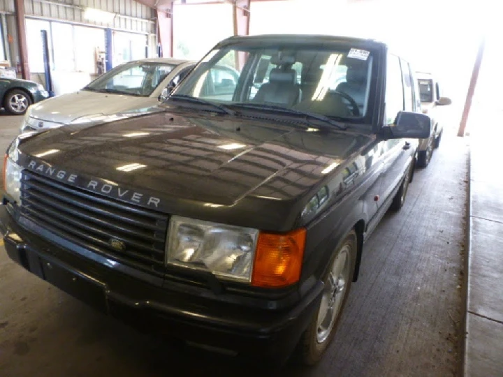 Black Range Rover in an auto wrecking yard.