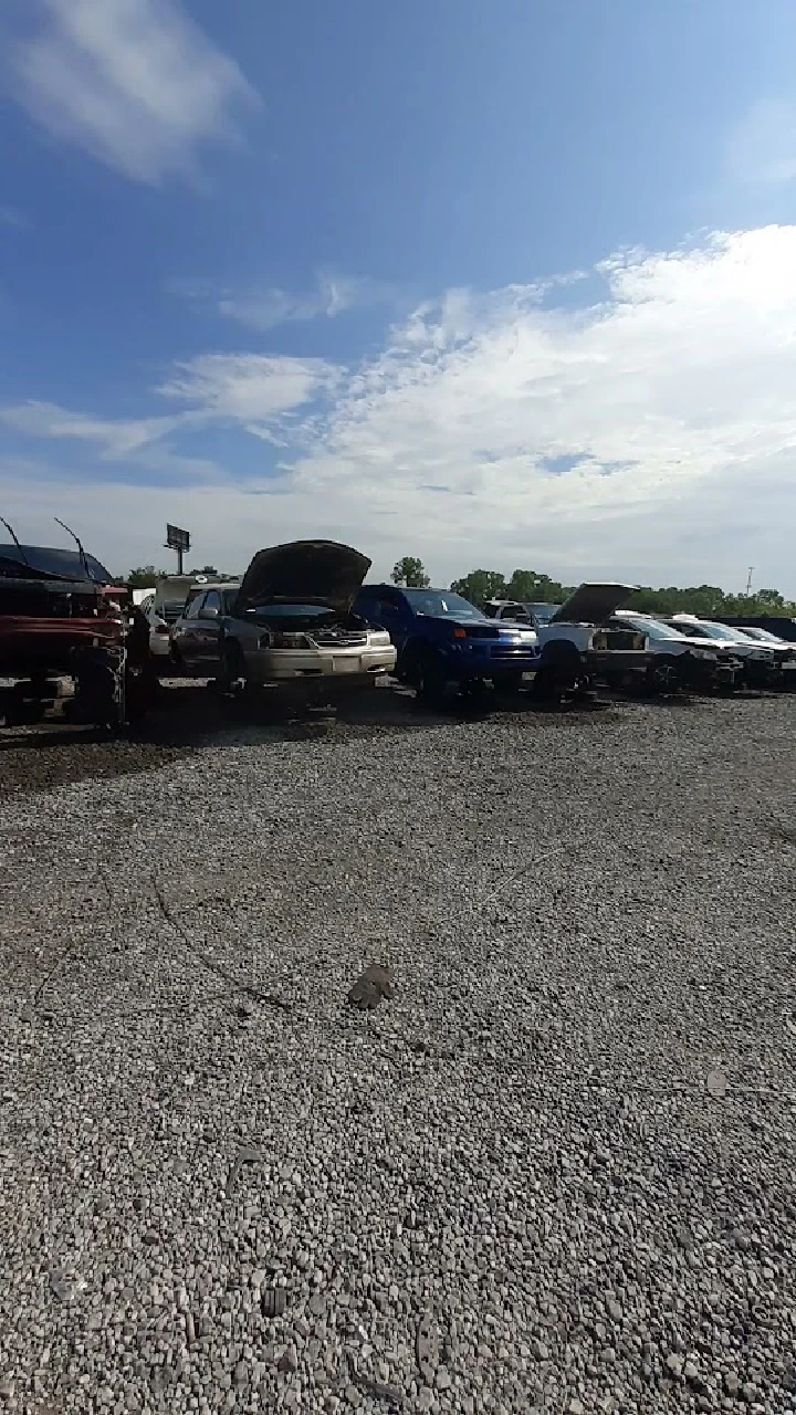 Cars in a junkyard under a clear blue sky.