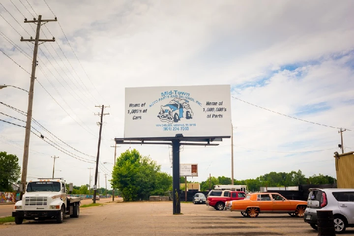 Mid-Town Auto Parts sign with cars and parts info.