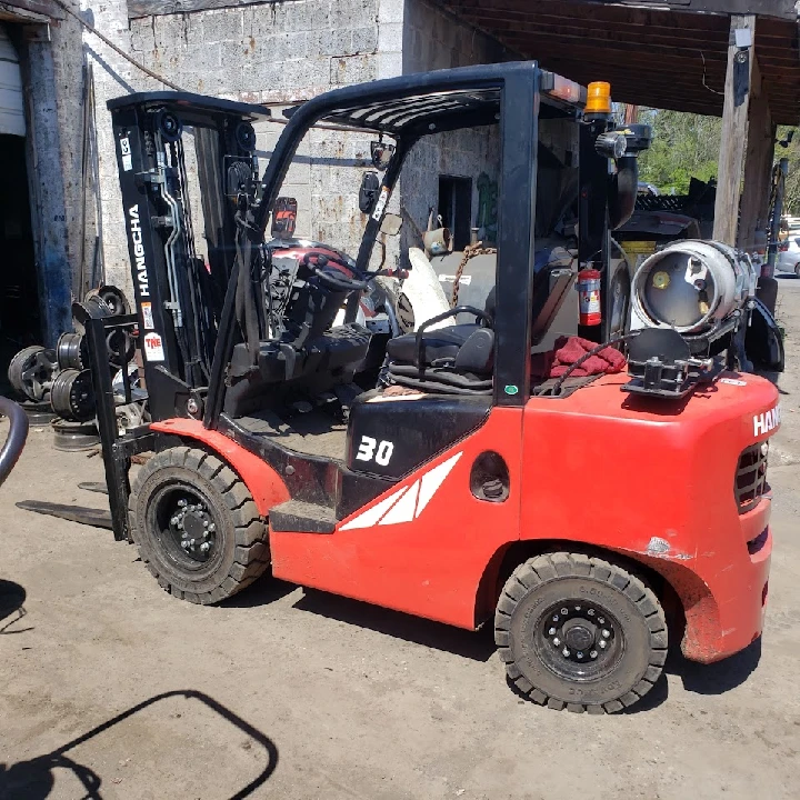 Red forklift parked in an auto recycling yard.