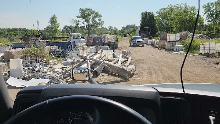 Scrap yard view with vehicles and metal piles.