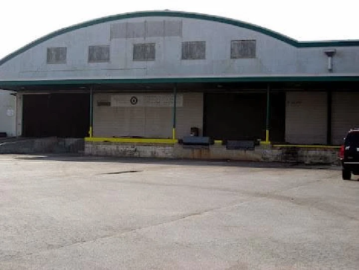 Warehouse exterior with loading docks and vehicles.