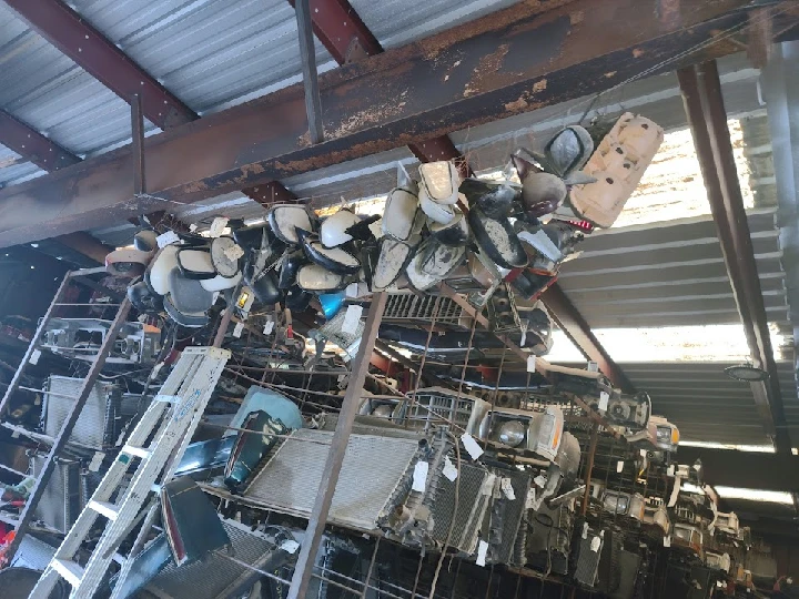 Auto parts hanging inside an industrial wrecking yard.