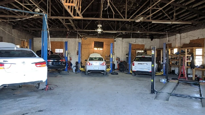 Auto salvage shop with vehicles on lifts and tools.