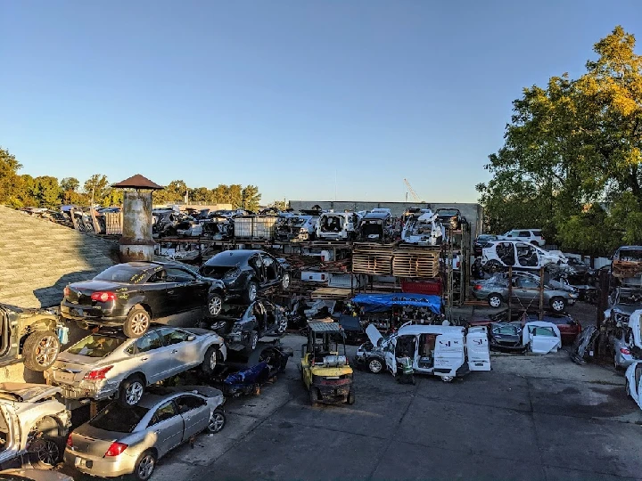 Auto salvage yard with stacked vehicles and parts.