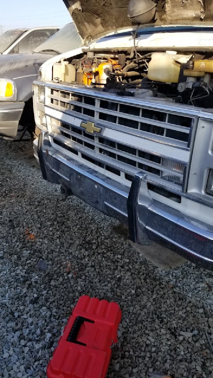 Chevy truck with hood open and toolbox nearby.