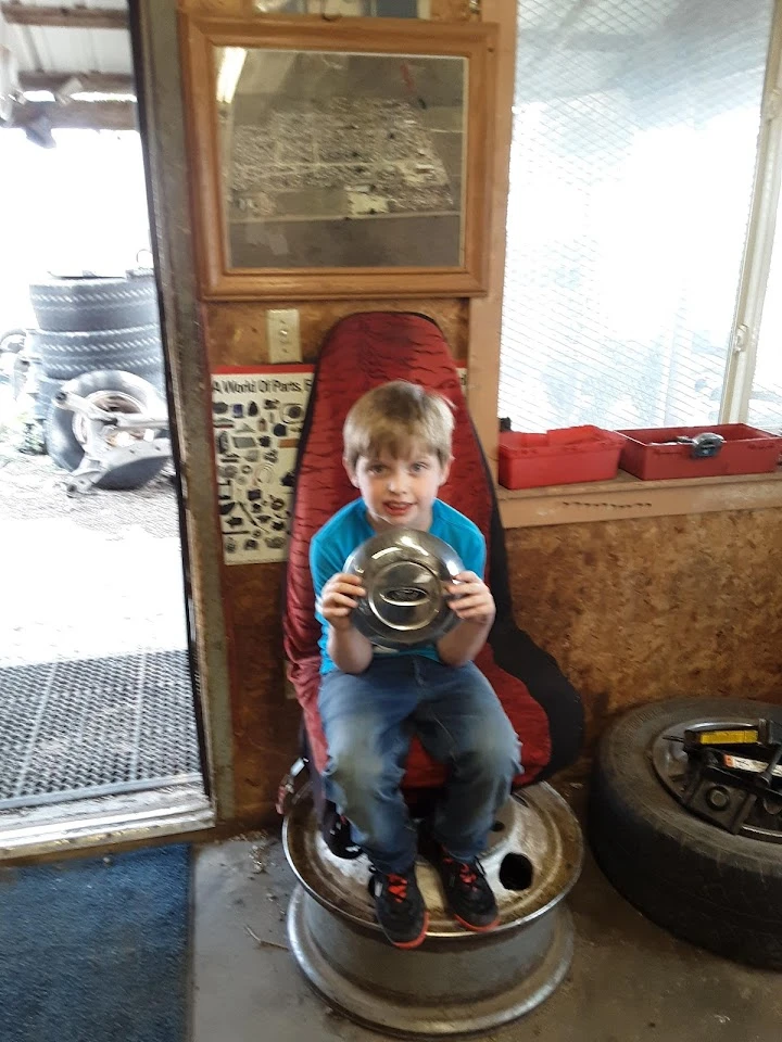 Child holding a car part in an auto parts shop.