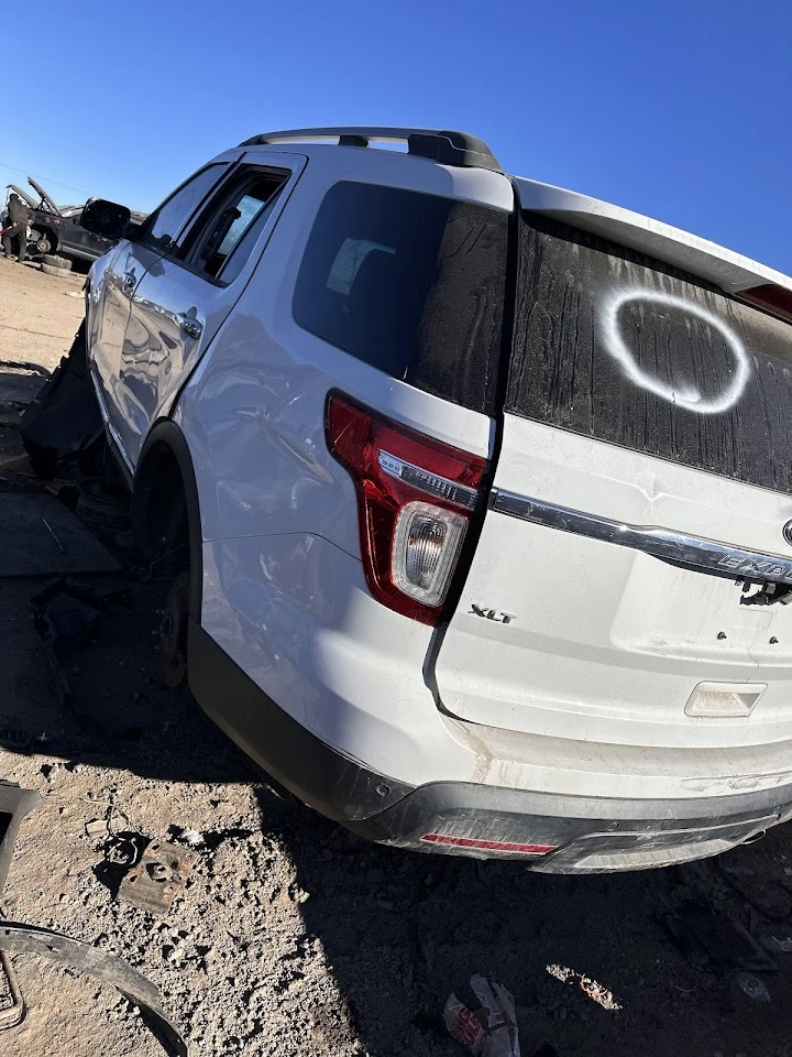 Damaged white SUV at a junkyard location.